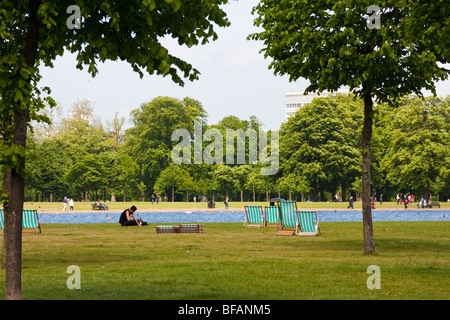 Liegestühle und Menschen sitzen um den runden Teich Stockfoto