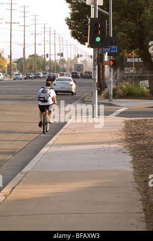 Ein Radfahrer fährt durch ein gelbes Licht auf Tustin Avenue in Orange, Kalifornien in Shorts, Flip-flops und einen Rucksack Stockfoto