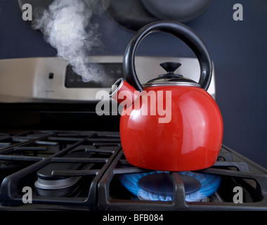 Eine rote Teekanne ist auf das Geschwür und Dampf aus der Tülle gießt. Stockfoto