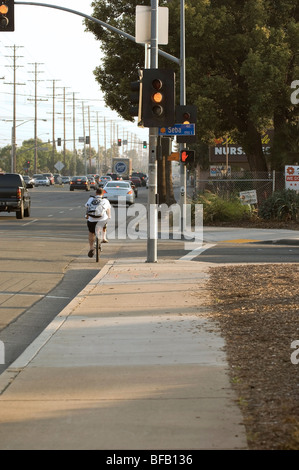 Ein Radfahrer fährt durch ein gelbes Licht auf Tustin Avenue in Orange, Kalifornien in Shorts, Flip-flops und einen Rucksack Stockfoto