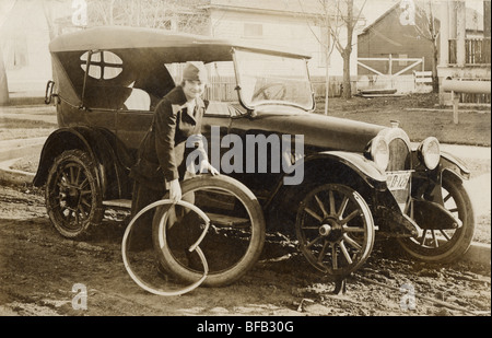 Frau Reifenwechseln auf Dirt Street Stockfoto