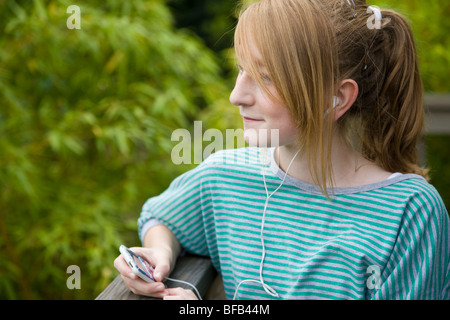 Ein junges Mädchen entspannt sich, während Sie Musik auf ihrem MP3-Player hören. Stockfoto