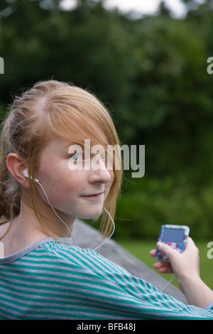 Ein junges Mädchen entspannt sich, während Sie Musik auf ihrem MP3-Player hören. Stockfoto