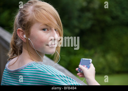 Ein junges Mädchen entspannt sich, während Sie Musik auf ihrem MP3-Player hören. Stockfoto