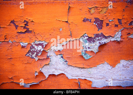 Nahaufnahme der abblätternden orangen Farbe an einer Wand Stockfoto