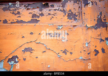 Nahaufnahme der abblätternden orangen Farbe an einer Wand Stockfoto