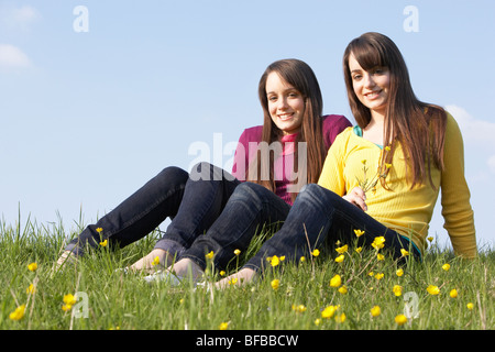 Zwei Mädchen im Teenageralter im Sommer Wiese sitzen Stockfoto
