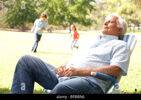 Entspannen im Park mit den Enkelkindern im Hintergrund Senior woman Stockfoto