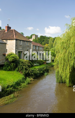 Häuser entlang dem Fluß Frome in Farleigh Hungerford mit Farleigh Castle im Hintergrund Stockfoto