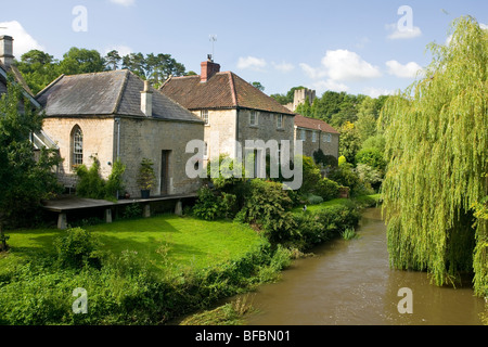 Häuser entlang dem Fluß Frome in Farleigh Hungerford mit Farleigh Castle im Hintergrund Stockfoto