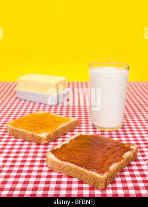 Zwei Scheiben Brot mit Marmelade, ein Glas Milch und ein Butter-Stick verteilt. Stockfoto