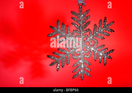 Glitzernde Schneeflocke Weihnachtsdekoration auf rotem Grund Stockfoto