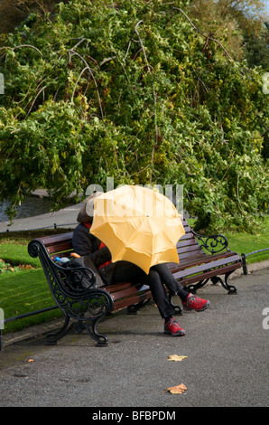 Frauenhäuser vor Wind und Regen unter einem Regenschirm in Stephens green Dublin Irland. Stockfoto