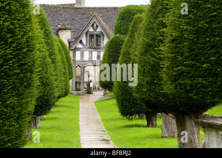 Zu den Lychgate auf dem Kirchhof von Str. Marys Kirche Painswick England Eiben. Stockfoto