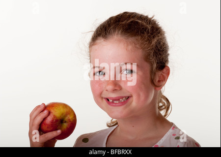 kleines Mädchen (7 Jahre alt), das vorderen Zähne zu essen Apfel vor weißem Hintergrund fehlt Stockfoto