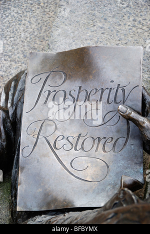 Nahaufnahme einer Bronzestatue zeigt einen Mann hält ein Stück Papier mit den Worten "Wohlstand wiederhergestellt" darauf geschrieben. Stockfoto