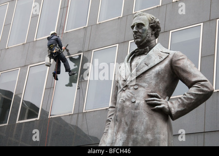 Statue von George Stephenson außerhalb Euston Station, London, mit Fensterreiniger bei der Arbeit Stockfoto