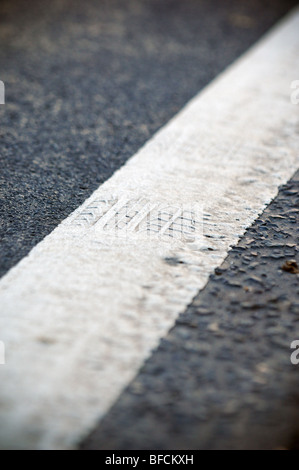 Eine weiße Linie auf einer UK-Straße ist mit einem Reifen Track Mark geprägt, die auf der Oberseite geschmolzen. Stockfoto