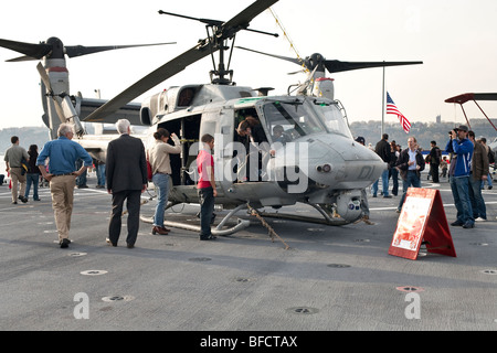 Besucher bewundern einen Marine Corps Huey Hubschrauber sitzen auf dem Flugdeck der USS New York, wie Frau von klettert Cockpit Stockfoto