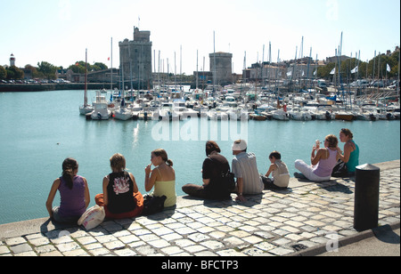 Jugendliche auf der Hafenmauer hoch über der Wasseroberfläche sitzend genießen Sie den Blick auf alten Hafen La Rochelle Stockfoto