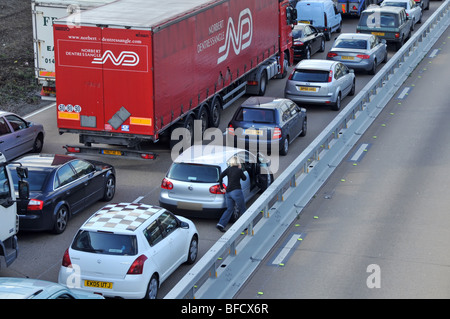 Adfial sieht den Autofahrer aus seinem Fahrzeug im blockierten Verkehr auf der Autobahn M25, nachdem er aufgrund eines Unfalls Essex England UK geschlossen hatte Stockfoto