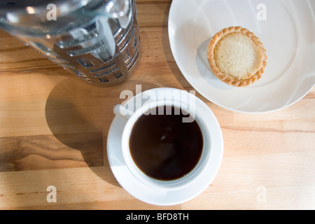 Tasse schwarzen Kaffee und ein Apfelkuchen, serviert auf Buche Tischplatte. Stockfoto