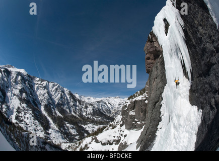 Ein Mann Eisklettern eine Steilwand mit Blick auf die Berge im Hintergrund in der Nähe von Ouray, Colorado. Stockfoto