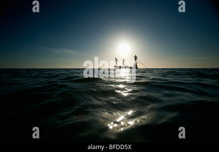 Ein paar Fische als ein Mann-Piloten ein kleines Boot in Florida. (Silhouette) Stockfoto