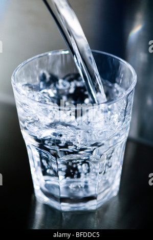 Nahaufnahme von Wasser in ein Glas gegossen wird Stockfoto