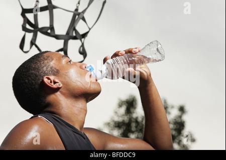 Junger Mann Getränke Wasser nach dem spielen Basketball in Barstow Park in Vermillion, South Dakota. (mit Blitz beleuchtet) Stockfoto