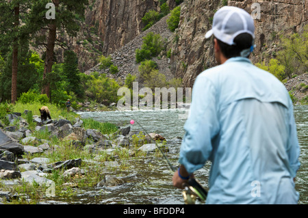Zwei Fischer beobachten einen Bären sorgfältig im Black Canyon National Park. Stockfoto