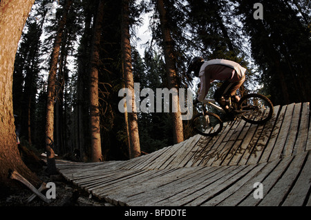 Ein Mann reitet auf seinem Mountainbike auf einem Holzsteg auf Teton Pass, Wyoming. Stockfoto