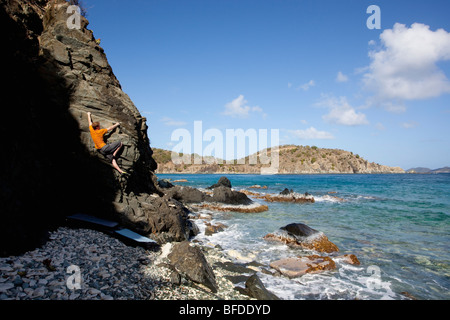 Ein Mann steigt aus dem Schatten an einem Strand Boulder Problem in der Karibik. Stockfoto