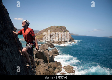 Ein Mann schaut beim Klettern traditionell einer neuen Route entlang einer abgelegenen Cay in den US Virgin Islands. Stockfoto