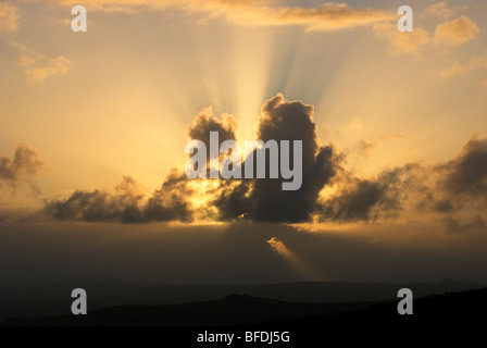 Sonnenstrahlen hinter dunklen Wolken bei Sonnenuntergang Stockfoto