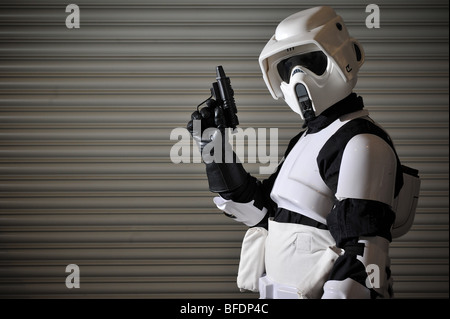 Ein Stormtrooper aus dem Star Wars Universum bereit für den Kampf, steht man vor einem gewellten Metallwand. Stockfoto