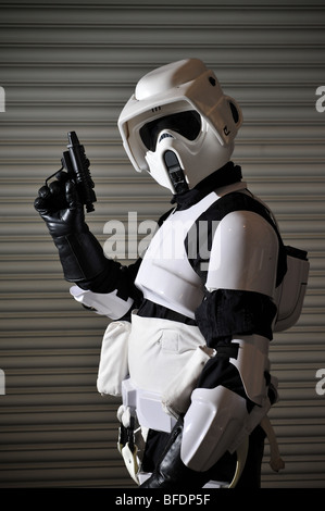 Ein Stormtrooper aus dem Star Wars Universum bereit für den Kampf, steht man vor einem gewellten Metallwand. Stockfoto
