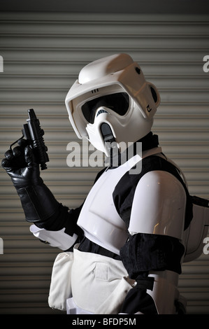 Ein Stormtrooper aus dem Star Wars Universum bereit für den Kampf, steht man vor einem gewellten Metallwand. Stockfoto