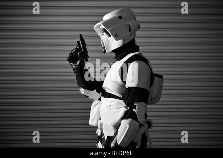 Ein Stormtrooper aus dem Star Wars Universum bereit für den Kampf, steht man vor einem gewellten Metallwand. Stockfoto