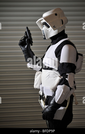 Ein Stormtrooper aus dem Star Wars Universum bereit für den Kampf, steht man vor einem gewellten Metallwand. Stockfoto