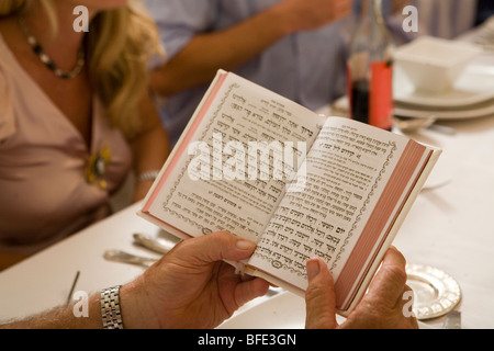 Mann hält ein Gebetbuch in einem festlichen Familienessen. Stockfoto