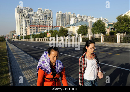 2 Damen, vorbei an einer Verbindung der luxuriösen Apartments und Villen in Songjiang am Stadtrand von Shanghai 2009 Stockfoto