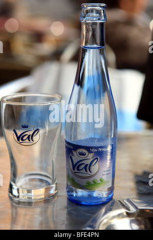 Flasche Wasser und ein leeres Glas auf einem Tisch in einem Straßencafé in Brüssel Stockfoto