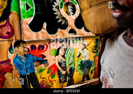 Ein Haitianer Straße Verkäufer vorbei an den kunstvoll bemalten Klapses Bus auf der Straße von Port-au-Prince, Haiti. Stockfoto