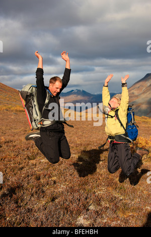 Wanderer, die einen Sprung in der Tundra bei Sonnenuntergang, Tombstone Territorial Park, Yukon, Kanada Stockfoto