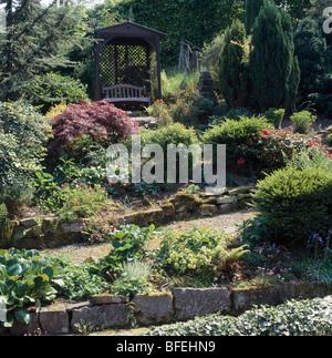 Großer Bauerngarten mit Sträuchern wachsen in Stein eingefasst Hochbeeten vor Holzpavillon Stockfoto