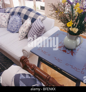 Malte blauen Tisch neben gestreiften Sofa mit blau + weiß geprüft und florale Kissen Stockfoto