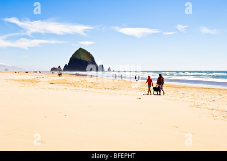 Paar walking Hund am Strand in der Nähe von Haystack Rock; Cannon Beach an der Küste Oregons. Stockfoto