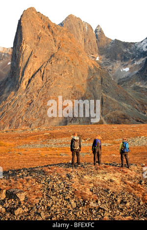 Drei Wanderer, die auf einem Felsen Türmen sich bei Sonnenuntergang mit Blick auf Mount Monolith in Tombstone Territiorial Park, Yukon. Stockfoto