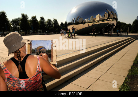 Eine junge Frau malt "die Bohne" Skulptur, oder cloudgate von Amish Kapur in Chicago, Millennium Park an einem heißen Sommertag. Stockfoto